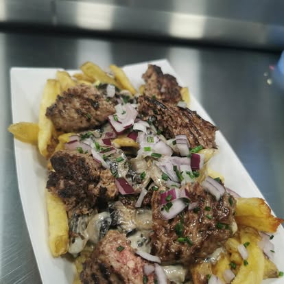 Assiette de frites maison garnies de viande grillée, sauce crémeuse et oignons rouges frais, servies par L’Authentik by Ju.