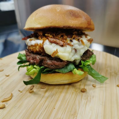 Burger maison avec double steak, salade fraîche, purée crémeuse et oignons grillés, servi par le foodtruck L’Authentik by Ju.