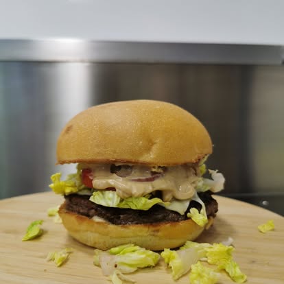 Burger maison du foodtruck L’Authentik by Ju avec steak, salade croquante et sauce crémeuse.